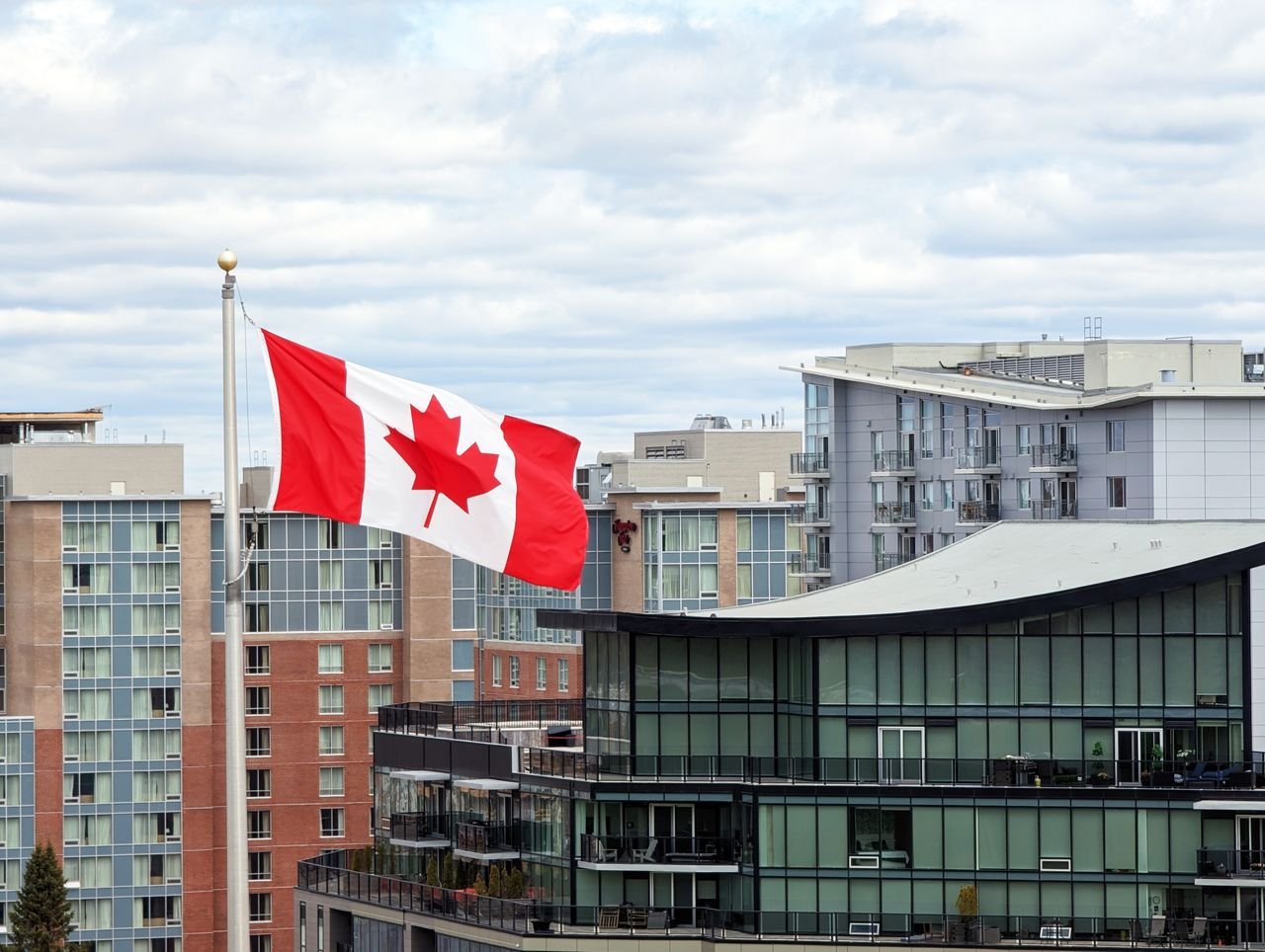 footer-cta-img Canadian flag waving prominently in Halifax skyline with modern architecture.